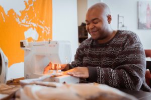 smiling black dressmaker working on sewing machine