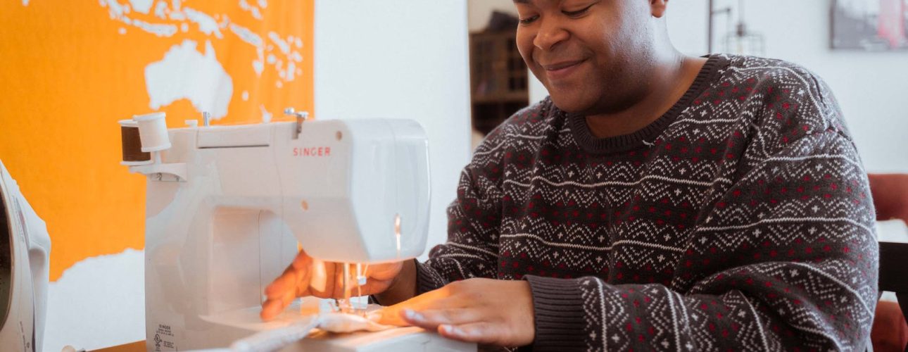 smiling black dressmaker working on sewing machine